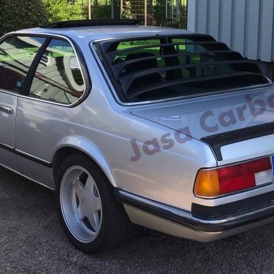 Carro BMW prateado clássico com persianas traseiras pretas e adesivo 'Jasa Carbon'