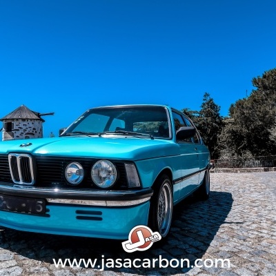 Carro desportivo clássico azul turquesa BMW numa estrada de pedra com texto www.jasacarbon.com