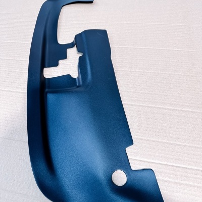 Componente automóvel de plástico preto com textura mate sobre fundo claro