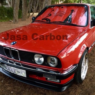 Carro BMW vermelho clássico estacionado numa área sombreada