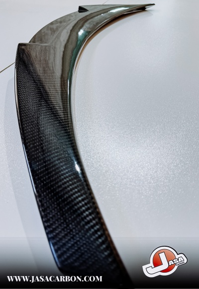 Peça automóvel em fibra de carbono com acabamento brilhante e padrão visível.