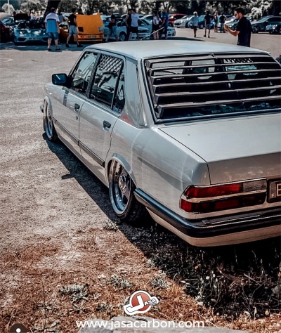 Carro sedan clássico prateado com rodas cromadas e persianas nas janelas traseiras