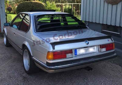 Carro BMW clássico cinza prateado com jantes brancas e persianas pretas nas janelas traseiras