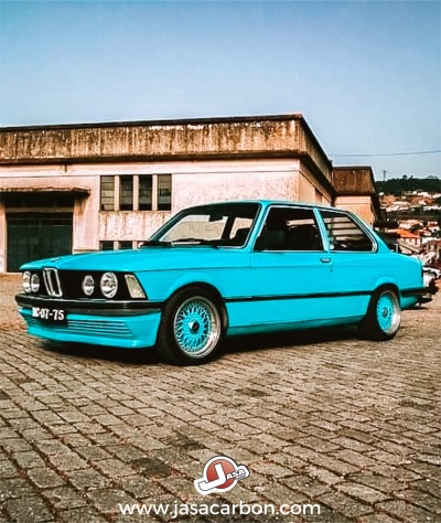 BMW clássico azul claro estacionado em calçada com edifício ao fundo