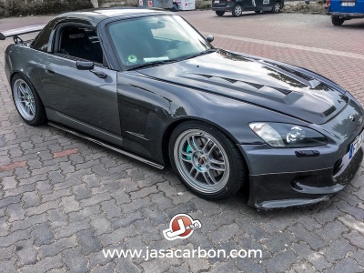 Carro desportivo cinza escuro estacionado em pavimento de blocos de cimento