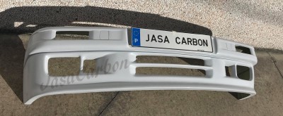 Para-choques de carro branco com etiqueta JASA CARBON sobre chão em pedra clara