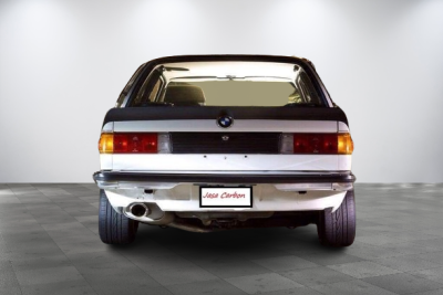 Carro BMW branco visto de trás em ambiente interno branco com chão de azulejos cinza