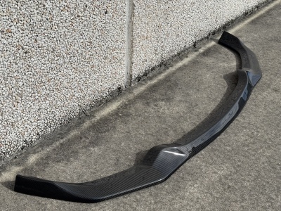 Spoiler dianteiro preto de fibra de carbono com fita azul no chão