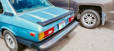 Parte traseira de carro antigo azul claro com pára-choques pretos e luzes traseiras vermelhas, brancas e âmbar