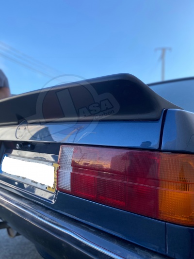 Parte traseira de um carro azul com farol traseiro vermelho e laranja, e spoiler preto