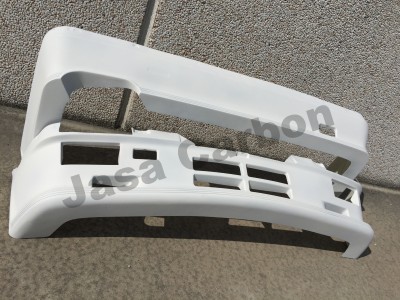 Para-choques dianteiros de plástico branco sobre chão cinza junto a parede