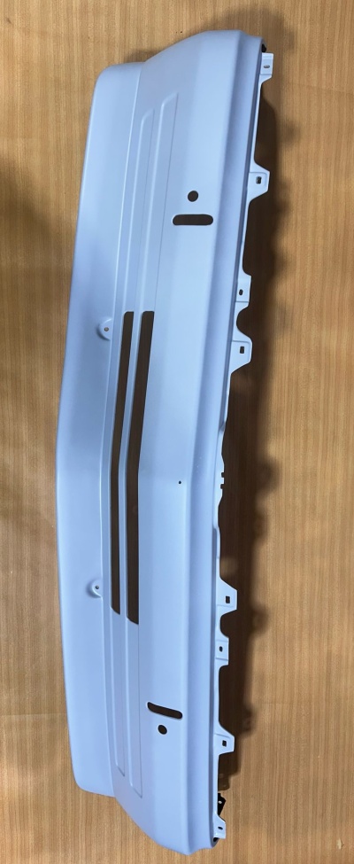 Peça branca de automóvel com encaixes sobre superfície de madeira clara