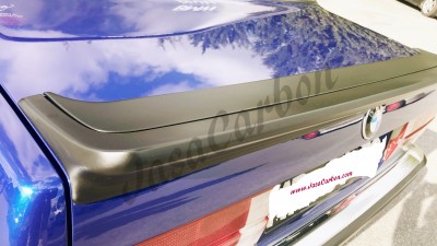 Spoiler traseiro em carbono preto fosco numa mala traseira azul brilhante de carro.