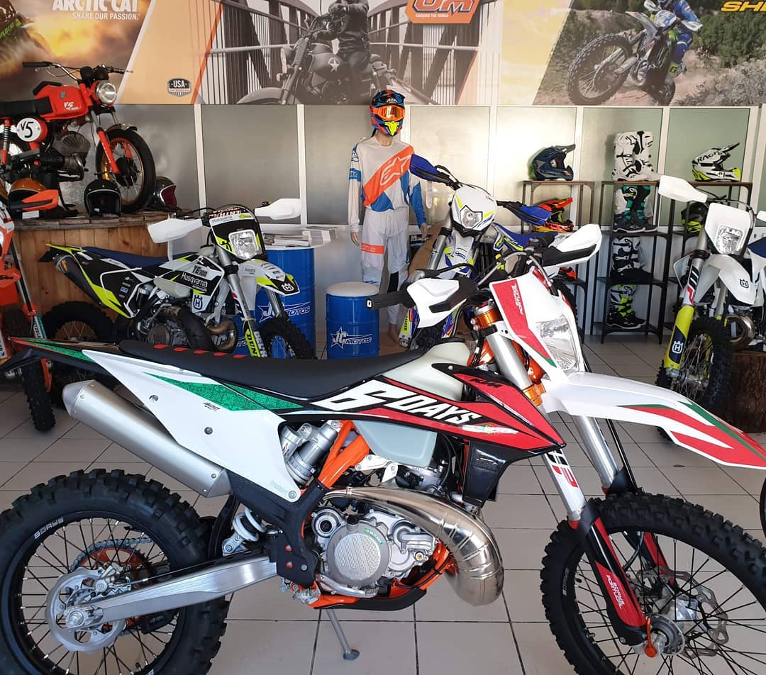 Motociclo todo terreno branco, vermelho e preto com texto '6 DAYS'