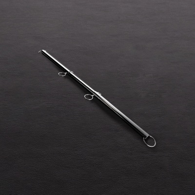 Barra metálica cromada com argolas sobre superfície preta