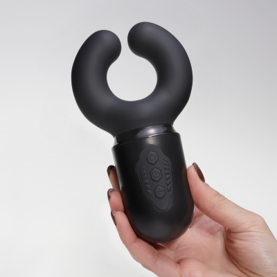 Dispositivo preto com forma em 'U' segurado por uma mão.