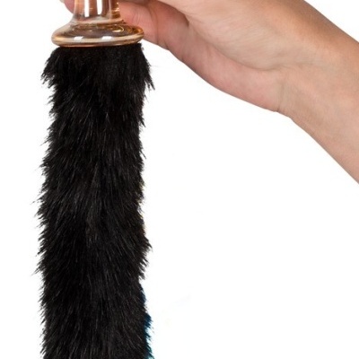 Plug anal transparente com cauda preta peluda sendo segurado por uma mão