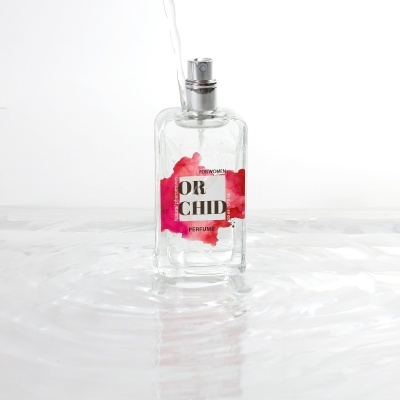 Frasco de perfume transparente com rótulo vermelho e rosa e texto ORCHID PERFUME