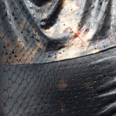 Tecido cinza e preto com textura de escamas e pontos brilhantes