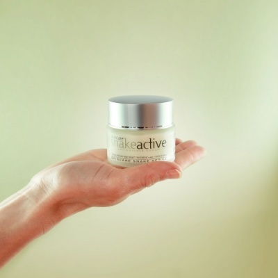 Frasco de creme para a pele em mão sobre fundo bege