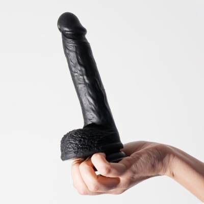 Dildo preto de silicone com base texturizada, segurado por uma mão