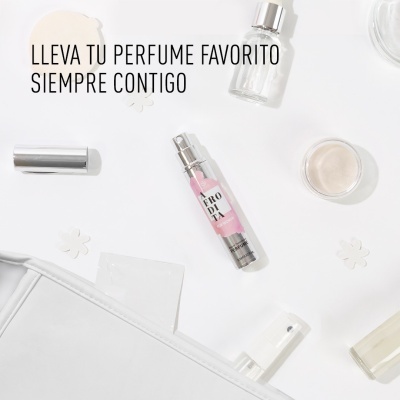 Frasco pequeno de perfume rosa com etiqueta ERODIA sobre superfície branca com cosméticos e texto em espanhol