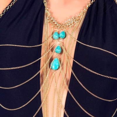 Colar de correntes douradas com pedras turquesa sobre roupa preta