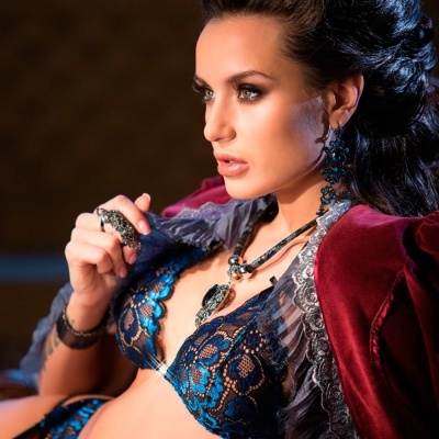 Mulher com lingerie azul de renda e casaco vermelho de veludo com acessórios pretos