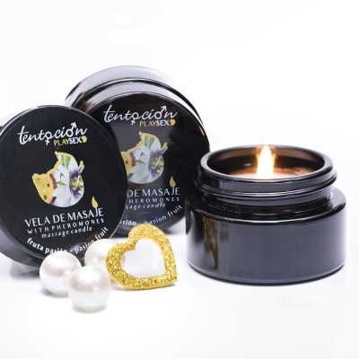 Vela de massagem em recipiente preto com tampa preta com texto e desenho, pérolas brancas e coração dourado