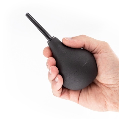 Pera de borracha preta com bico preto na mão sobre fundo branco