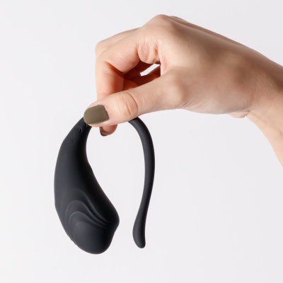 Dispositivo preto curvo com textura lisa e ondulações, segurado por uma mão