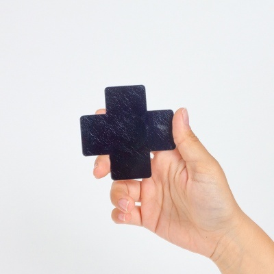 Mão a segurar peça preta em forma de cruz