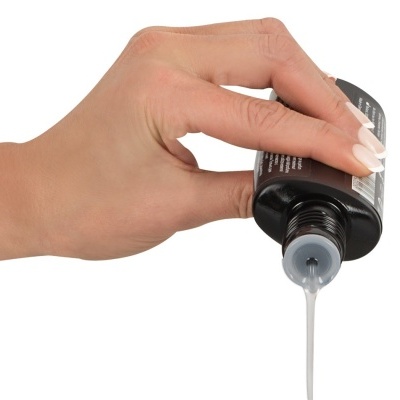 Mão segurando frasco preto a verter líquido branco