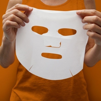 Máscara facial branca de tecido fino com recortes para olhos, nariz e boca