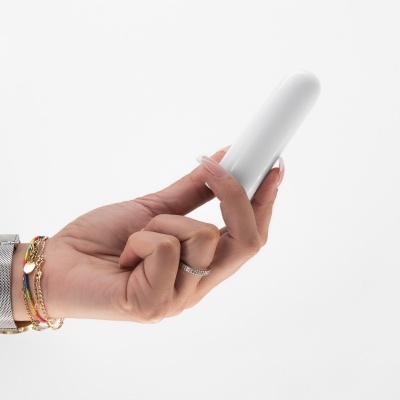 Mão segurando vibrador branco liso em fundo branco