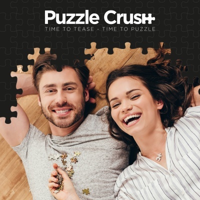 Homem e mulher sorrindo com peças de puzzle ao redor no chão de madeira clara