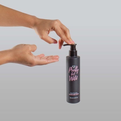 Frasco preto 'Pretty but Wild' com doseador e mãos ao lado