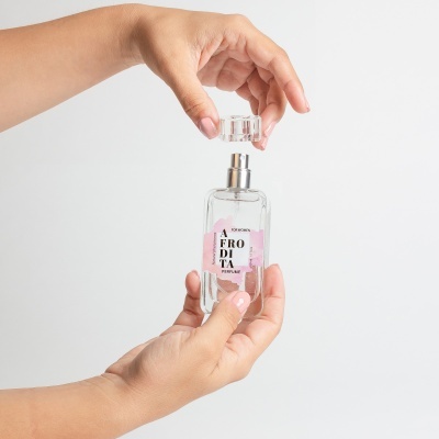 Frasco de perfume transparente com tampa removível segurado por mãos