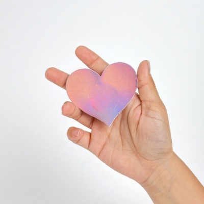 Mão a segurar coração de papel rosa e roxo em fundo branco