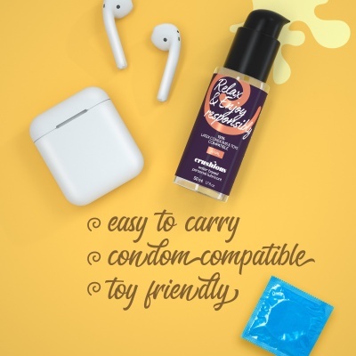 Frasco de óleo lubrificante, preservativo azul embalado, auriculares e estojo branco num fundo amarelo