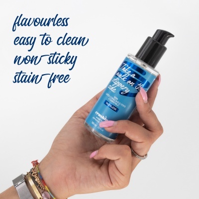 Frasco líquido azul com tampa de bomba preta com texto e mão segurando sobre fundo branco