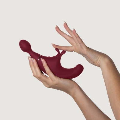 Produto sexual silicone vinho tinto mãos femininas fundo cinza claro
