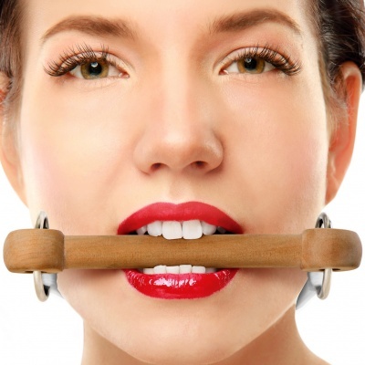 Mulher com batom vermelho segura objeto de madeira na boca em fundo branco