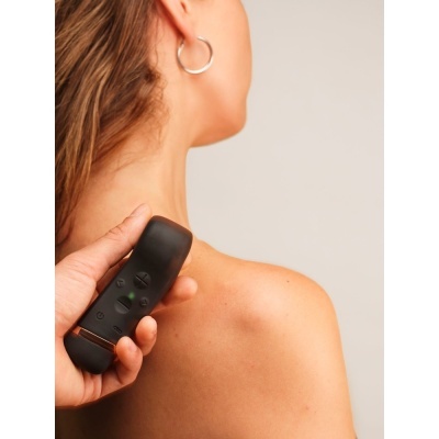 Pessoa de costas com aparelho preto a ser aplicado no ombro