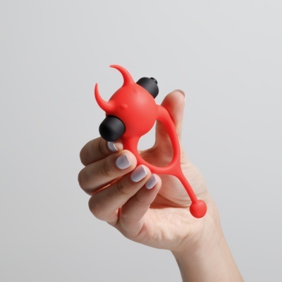 Mão segurando objeto vermelho em forma de diabo com detalhes pretos