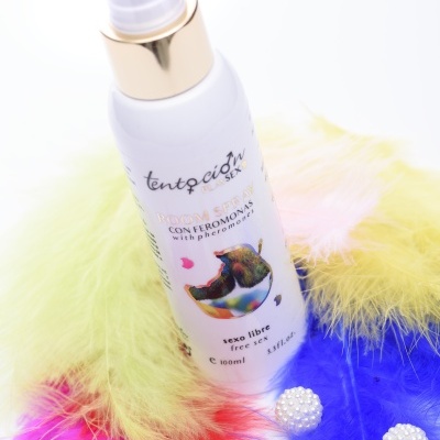 Frasco branco com tampa dourada e penas coloridas ao redor