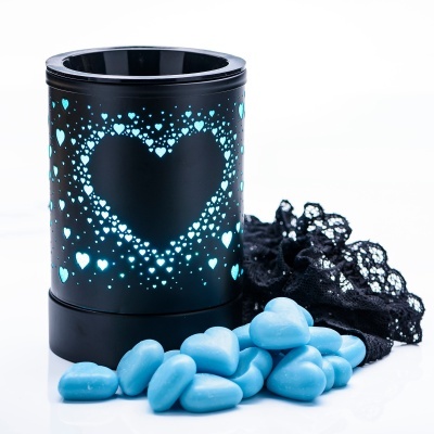 Vela preta com luz azul em forma de coração, corações de cera azul e renda preta ao fundo