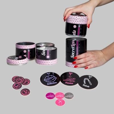 Jogo de cartas eróticas em caixa redonda preta com bolinhas cor-de-rosa e cartas redondas com ícones e texto em inglês.