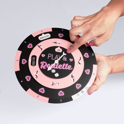 Jogo de tabuleiro circular rosa e preto com texto 'PLAY & Roulette' e ilustrações de corações