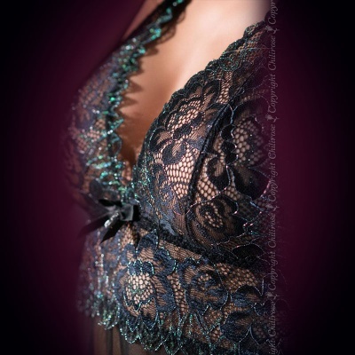 Soutien de renda preta com detalhes verdes e fita preta em fundo escuro blurado